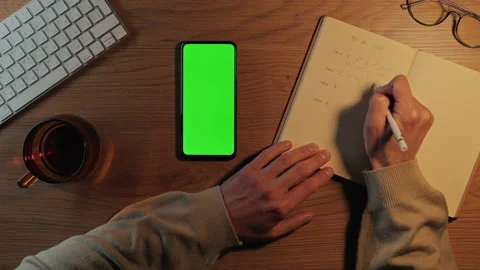 Man writing in planner and using mobile with green screen Stock Footage 162836915