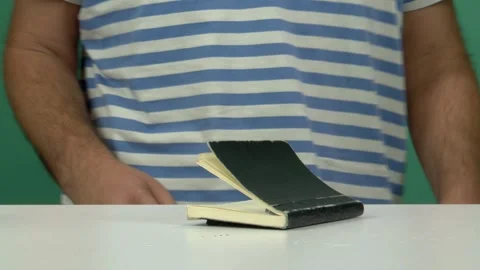Man Writing in Small Black Notebook on White Table with Green Screen Background Stock Footage 344677370