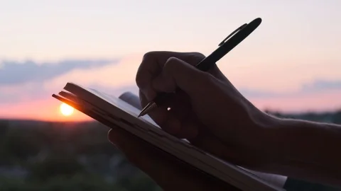 A man is writing something in a notebook at sunset, close up 스톡 동영상 112011460
