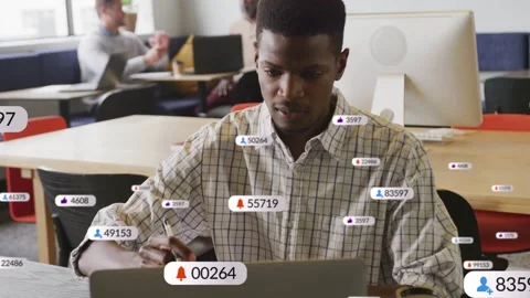 Man writing in study sparking floating badges around him and laptop, typing Stock Footage 336714380