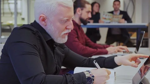 Man writing while reading from tablet in the office Stock Footage 128652400