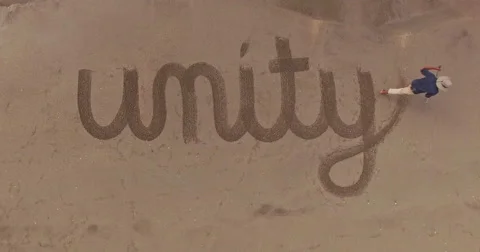 Man writing the word unity in the sand Video stock 65560496