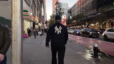 Man with Yankee jacket walking in Midtown Empire State Building Manhattan NYC 스톡 동영상 164479131