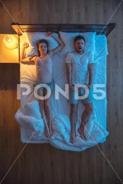 The man yawn near the woman on the bed. evening night time. view from above Stock Photos