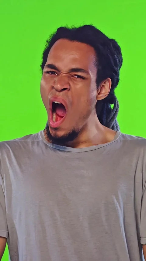 Man yawning in studio with bright green backdrop, fatigue mood and energy shift Stock Footage 333366564