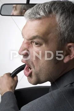 A man yelling over his shoulder whilst driving a car Stock Photos