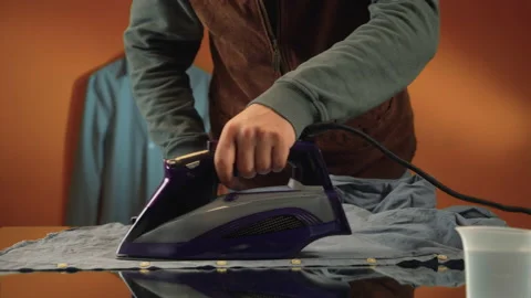 Man on yellow background ironing gray shirt Stock Footage 171585332