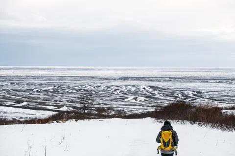A man with yellow backpack walking on snow mountain in winter, at Iceland Stock Photos