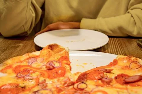 Man in yellow clothes at table in front of large dish with freshly baked pizz Stock Photos