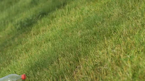 A man in yellow gloves, removing garbage from the green grass Stock Footage 136850699