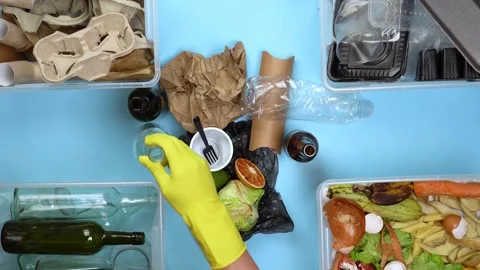 A man in yellow gloves sorts garbage. Video stock 130490767