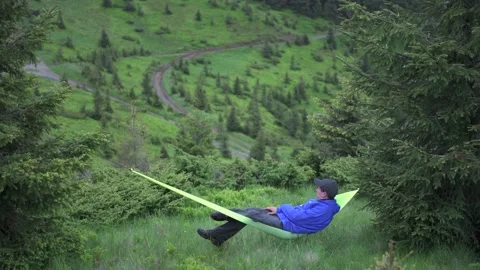 Man on yellow hammock in summer mountains Stock Footage 145651235