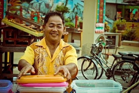 Man in yellow holding a stack of container Stock Photos