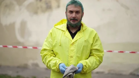 A man in a yellow jacket and gloves puts on a gas mask in the street Stock-Footage 132634650