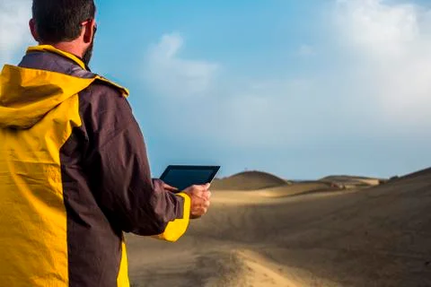 Man with yellow jacket explore the desert and look the map and the gps point  Stock Photos