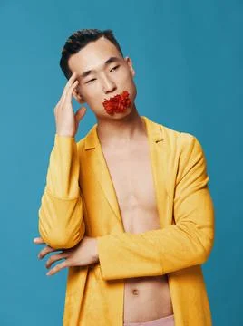 A man in a yellow jacket on a naked body and a red flower in his mouth Stock Photos