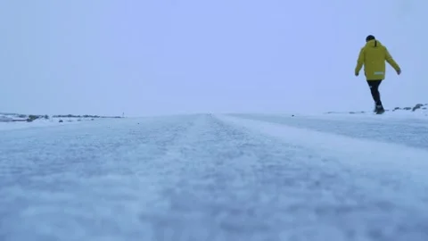 Man in yellow jacket running down the frozen road Stock Footage 301075415