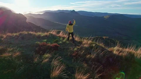 The man in the yellow jacket runs to the top of the mountain at sunrise, rais Video stock 220521934
