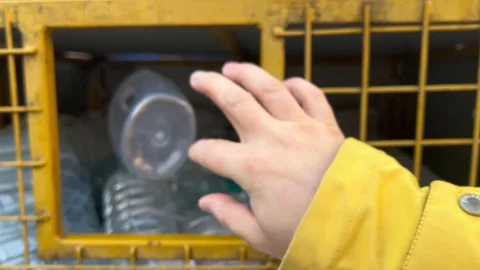 Man in yellow jacket throws clear plastic soda bottle into trash box Stock Footage 274242845