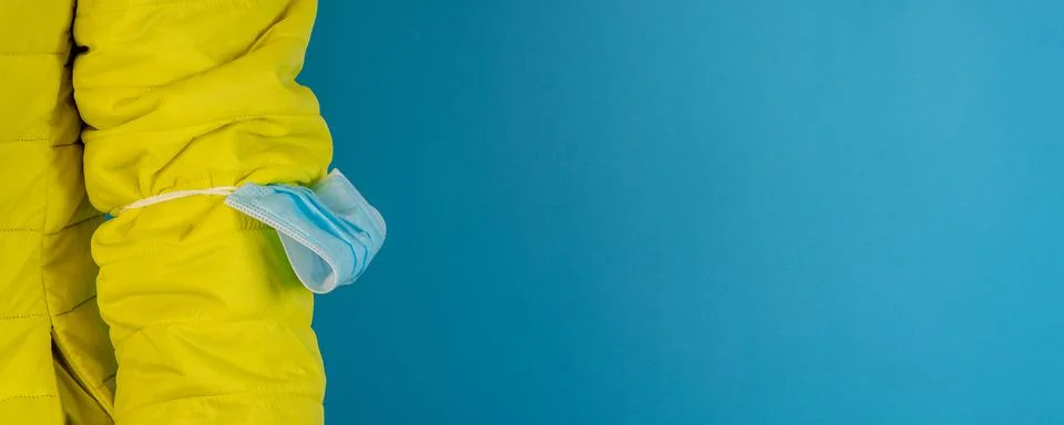 Man in yellow jacket is using a protective mask against corona virus on blue  Stock Photos