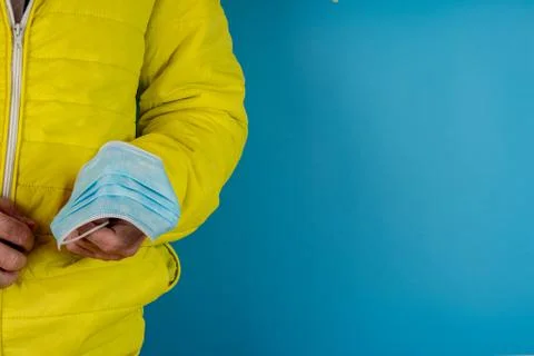 Man in yellow jacket is using a protective mask against corona virus on blue  Stock Photos