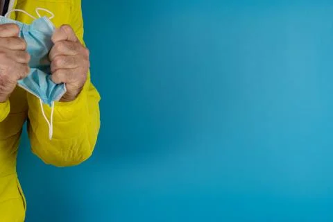 Man in yellow jacket is using a protective mask against corona virus on blue  Stock Photos