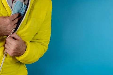 Man in yellow jacket is using a protective mask against corona virus on blue  Stock Photos