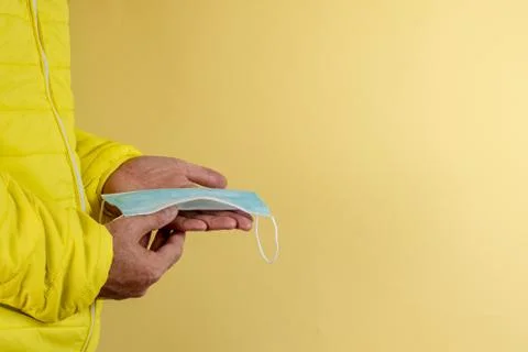 Man in yellow jacket is using a protective mask against corona virus on yello Stock Photos