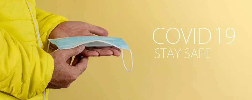 Man in yellow jacket is using a protective mask against corona virus on yello Stock Photos