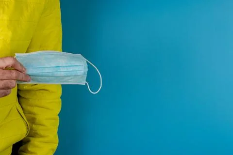 Man in yellow jacket is using a protective mask against corona virus on blue  Stock Photos