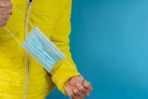 Man in yellow jacket is using a protective mask against corona virus on blue  Stock Photos