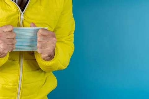 Man in yellow jacket is using a protective mask against corona virus on blue  Stock Photos