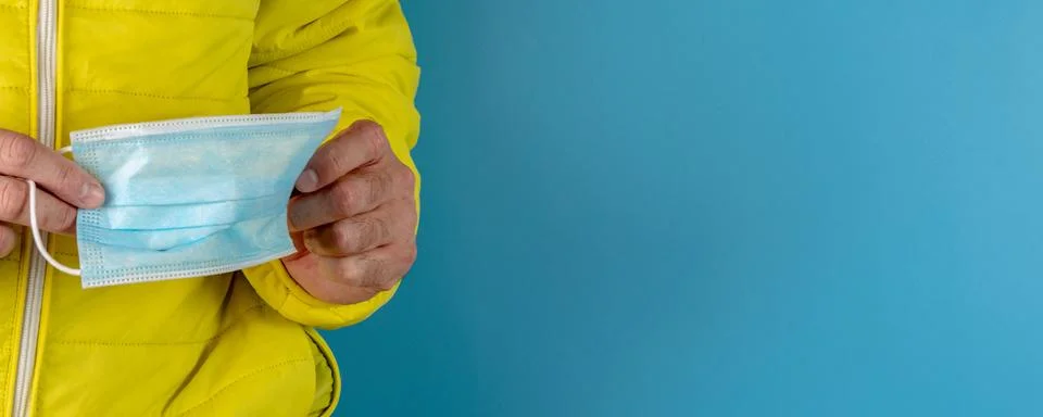 Man in yellow jacket is using a protective mask against corona virus on blue  Foto stock