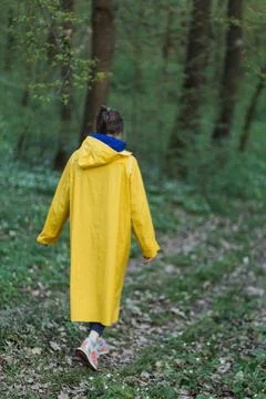A man in a yellow raincoat walks through the forest Stock Photos