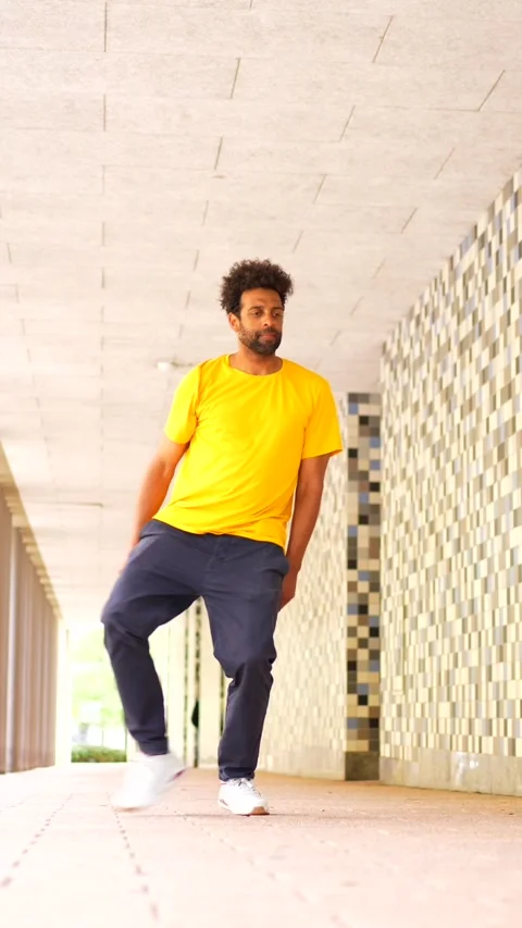 A man in a yellow shirt and blue pants is walking down a hallway Stock Footage 277650153