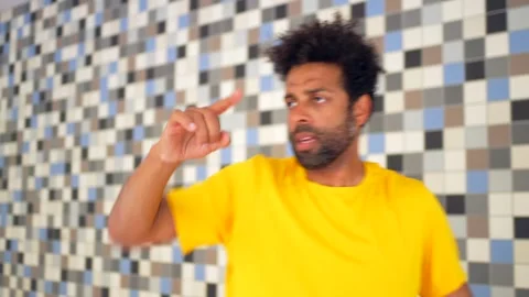 A man in a yellow shirt is standing in front of a wall with a blue Stock Footage 277647971