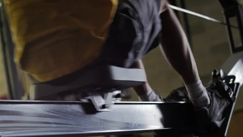 Man in yellow shirt workouts on rowing machine at gym for fitness routine Stock Footage 312758668