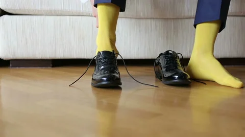 The man in a yellow socks wears shoes to tie shoelaces Stock Footage 44686014