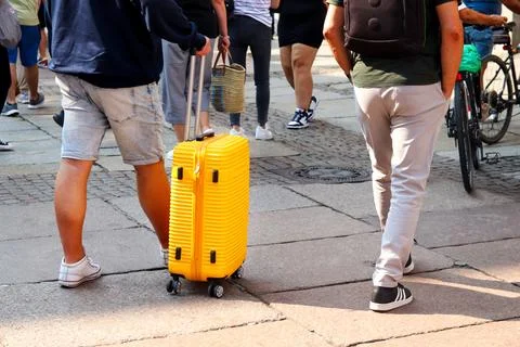 Man with a yellow suitcase, navigating through a busy city street. The man .. Stock Photos