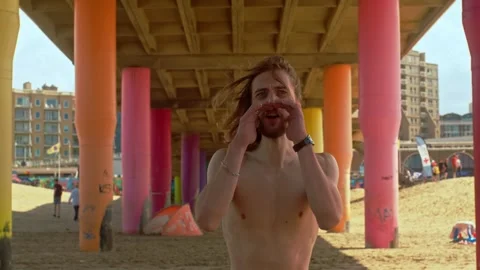 A Man Yells Beneath a Pier on the Beach - Close Up Stock Footage 288491820