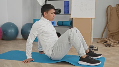 Man on yoga mat performs reverse plank with hands on floor in studio, weari.. 스톡 동영상 337431261