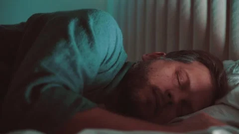 A man is a young man sleeping in a bed at night Video stock 257689464