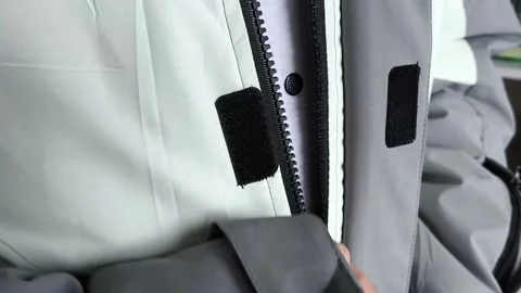 A man zips up a warm winter jacket in close-up. Down jacket for cold weather. Stock Footage 325034021