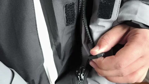 A man zips up a warm winter jacket in close-up. Down jacket for cold weather. Stock Footage 325034093