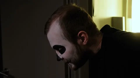 A man in zombie make-up walks uncertainly leaning on walls. Close-up. Halloween. Stock Footage 142075997