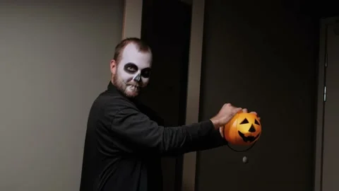 A man in zombie makeup is dancing with a pumpkin lantern. Halloween eve. Stock Footage 142076801