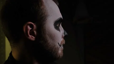 The man in zombie makeup walks, stops, looks around and leaves frame. Close-up. 스톡 동영상 142076308