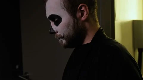 A man in zombie makeup walks, stops,sniffs and leaves frame. Close-up. Halloween Video stock 142076161