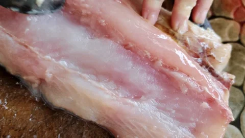 Management Raw fish meat scraped with a spoon on a wooden cutting board Stock Footage 305258940
