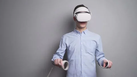 Manager against a gray wall uses a futuristic virtual reality Headset Stock Footage 166443557